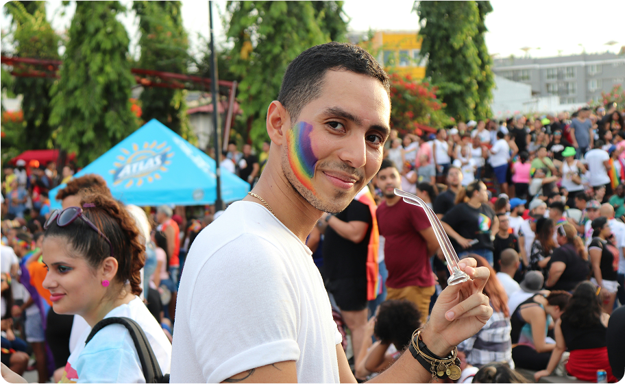 Individual smiling in a crowd with a rainbow painted on the face