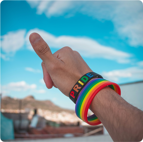Person holding their hand up to the sky with pride bracelets