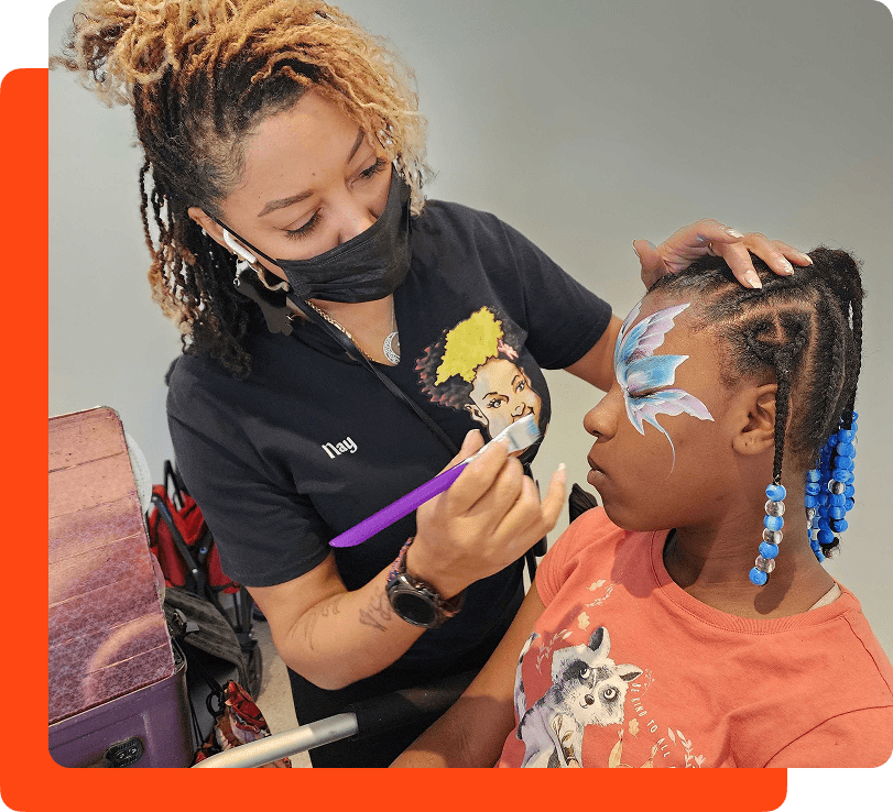 Volunteer applying face paint to a child's face at a NCCHR event